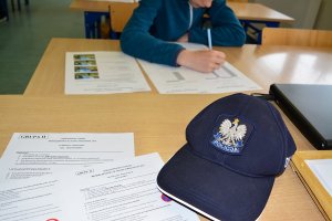 czapka policyjna na tle testów egzaminacyjnych