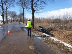 Na pierwszym planie podchodzący do samochodu który jest w rowie policjant, na drugim planie policjant techniki kryminalistycznej